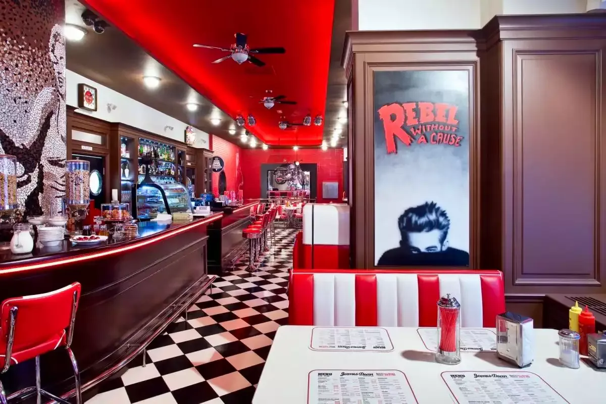 Prostřený stůl v boxu s výhledem na bar a plakát Rebel Without a Cause