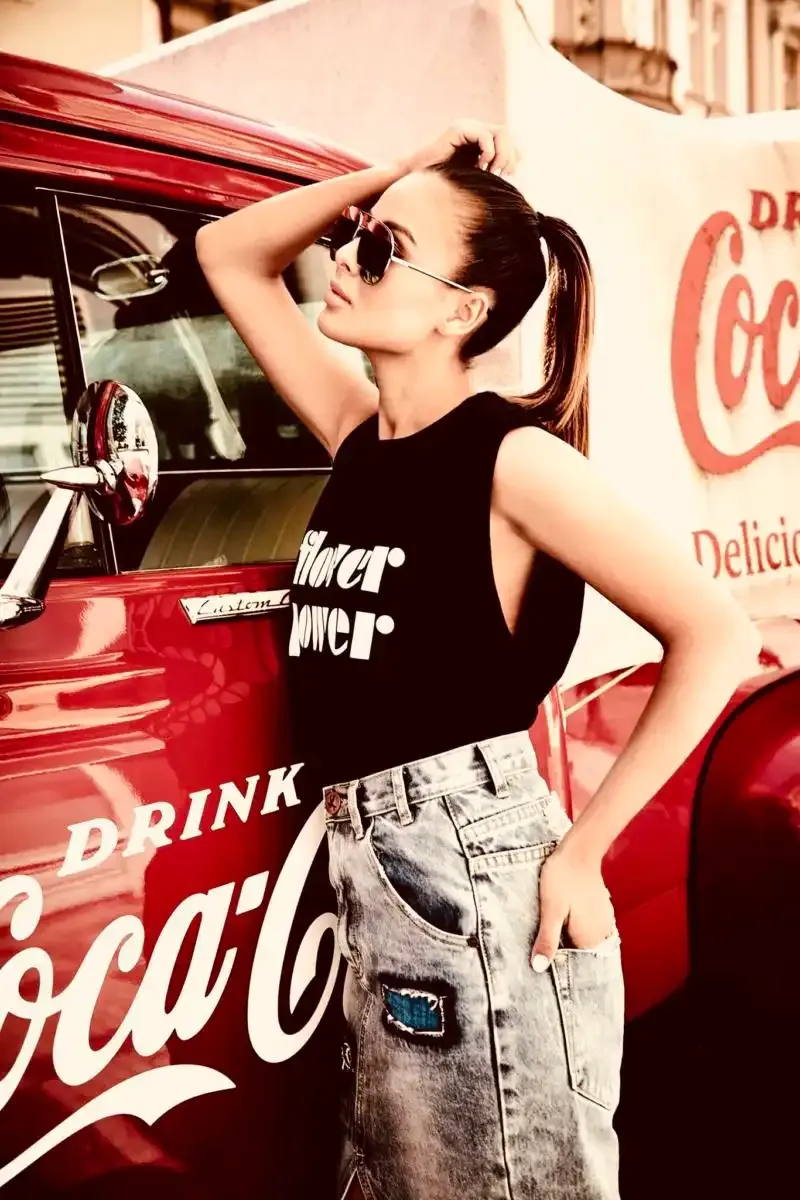 Modelka ve slunečních brýlích u červeného veteránu s nápisem Drink Coca-Cola