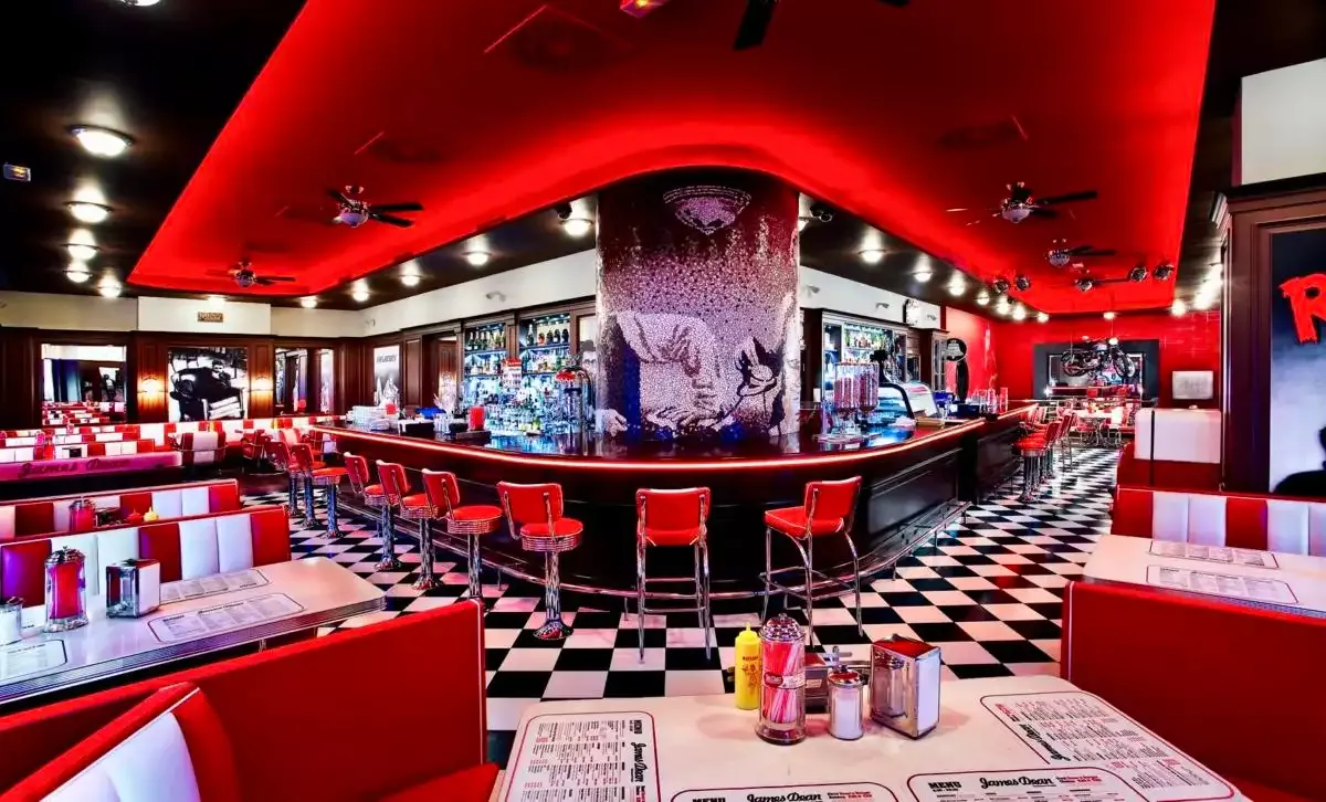 Celkový pohled na diner: bar do oblouku, červené boxy a mozaikový sloup uprostřed