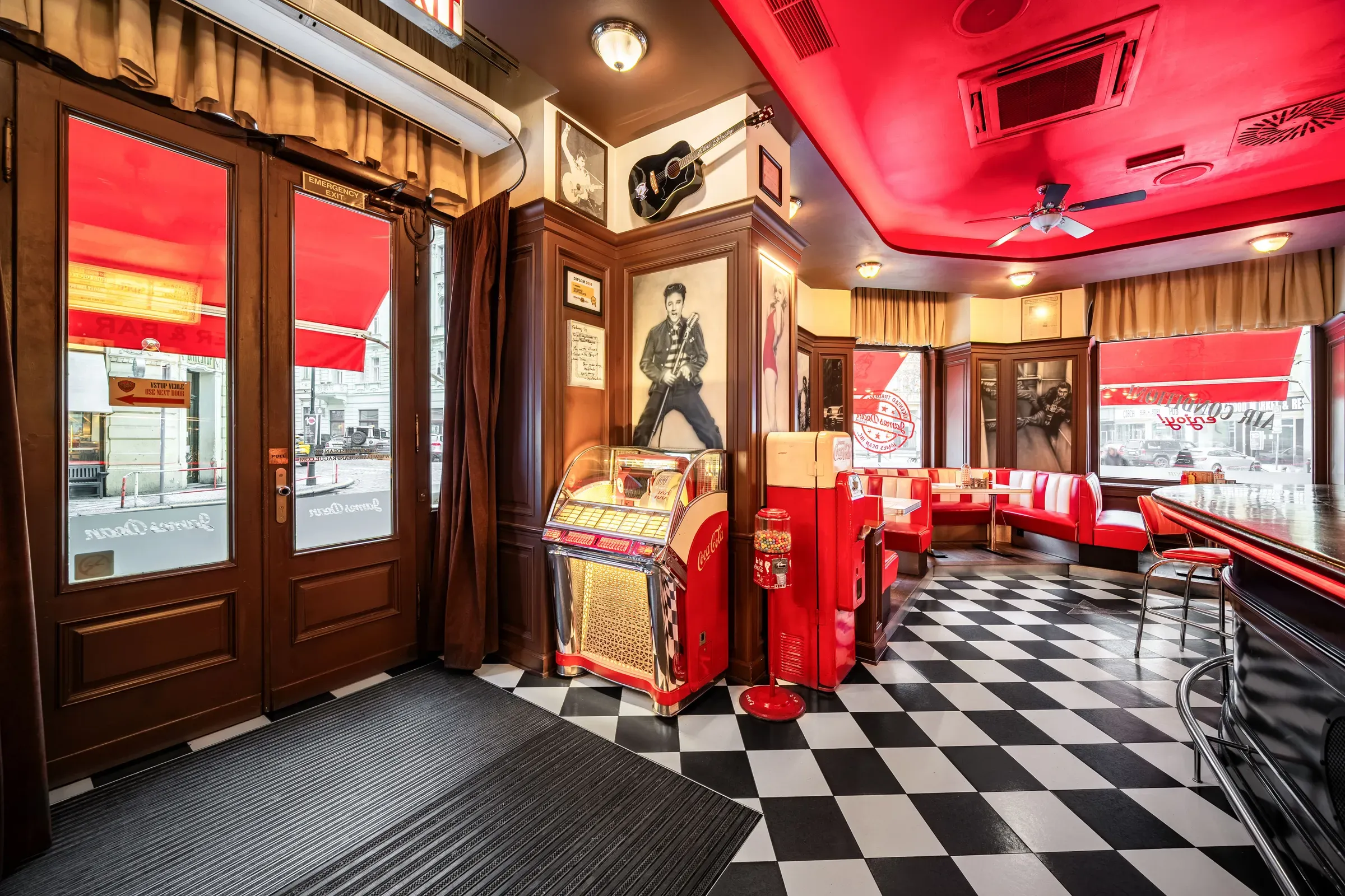 Vchod do dineru s jukeboxem, plakáty a červenými boxy