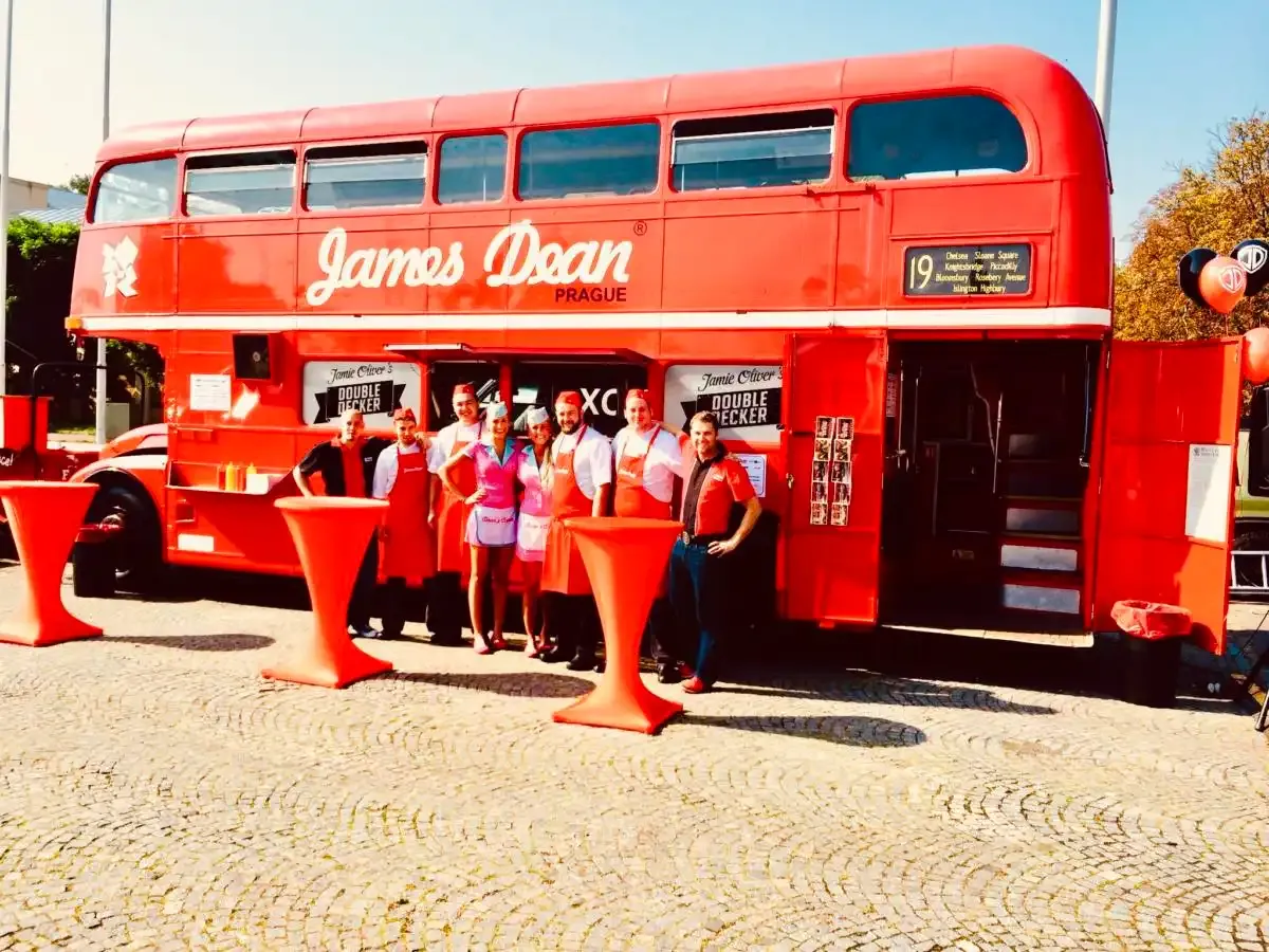 Červený patrový autobus James Dean Prague s týmem a červenými koktejlovými stolky