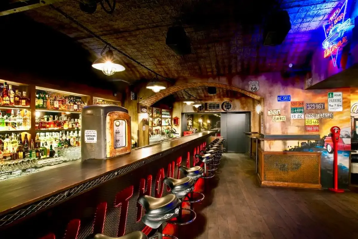 Bar Music Clubu s chromovanými stoličkami, poznávacími značkami a modrým neonem