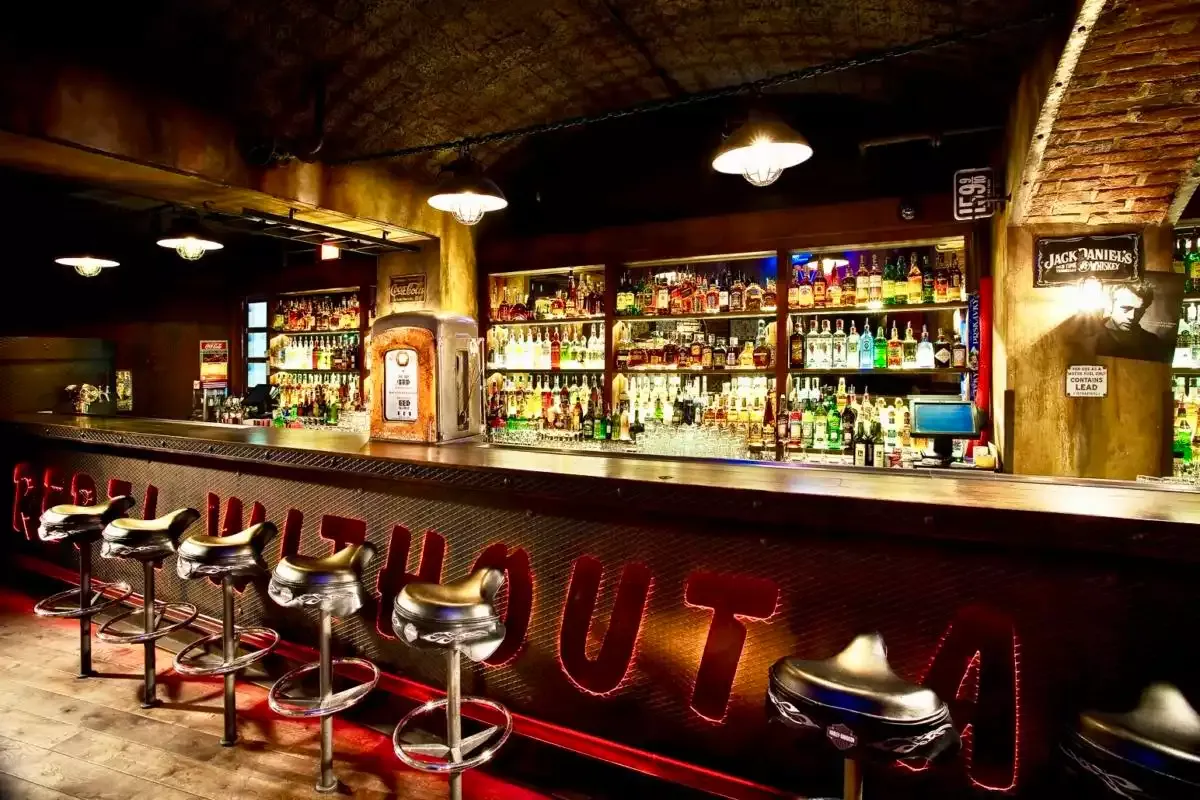 Dlouhý bar Music Clubu pod cihlovou klenbou s nápisem Rebel Without a Cause