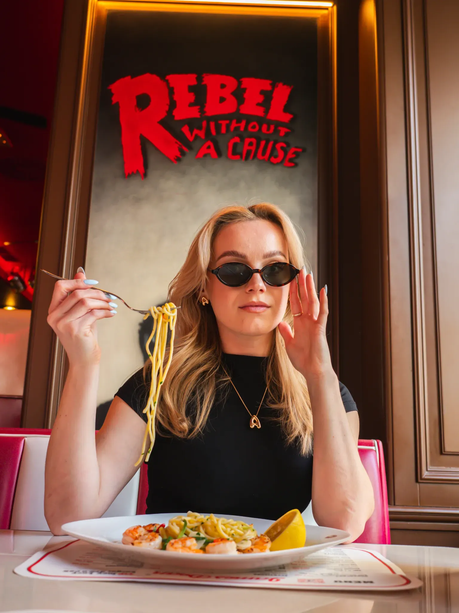 Host ve slunečních brýlích se špagetami pod nápisem Rebel Without a Cause